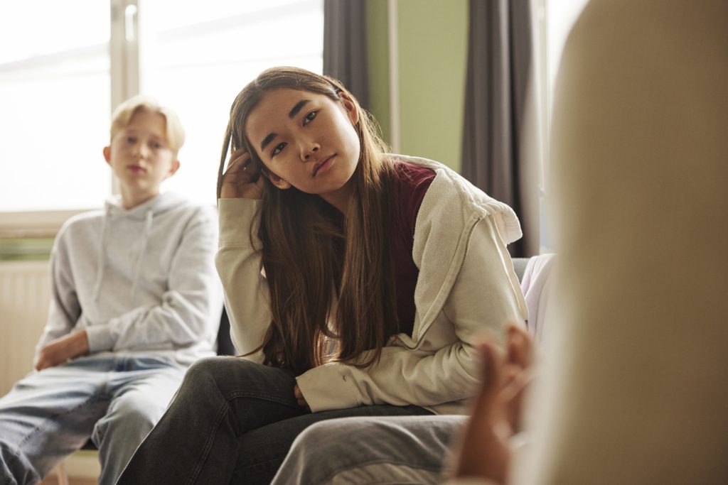 Long haired teenage female student attending group therapy in school Intensive Outpatient Programs (IOP)