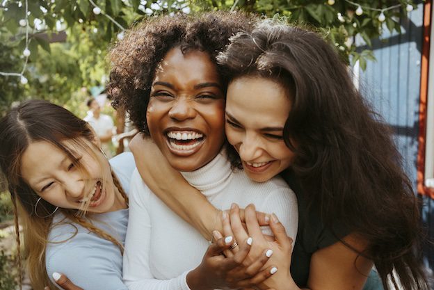 group of young girls hugging each other and laughing